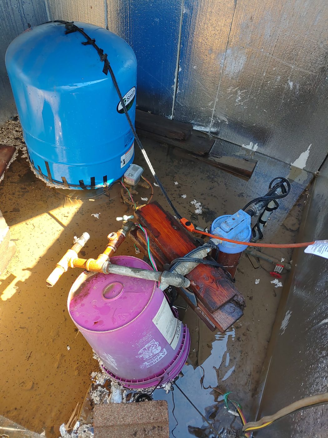 Our well house after Winter Storm Uri — the blue pressure tank, electric pump, and pipe plumbing that stopped working when the grid went down in February 2021